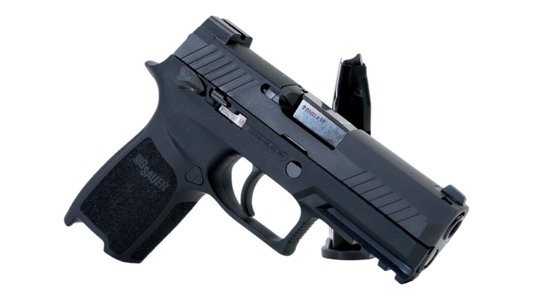 Side view of a black SIG Sauer semi-automatic pistol with a detachable magazine on a white background
