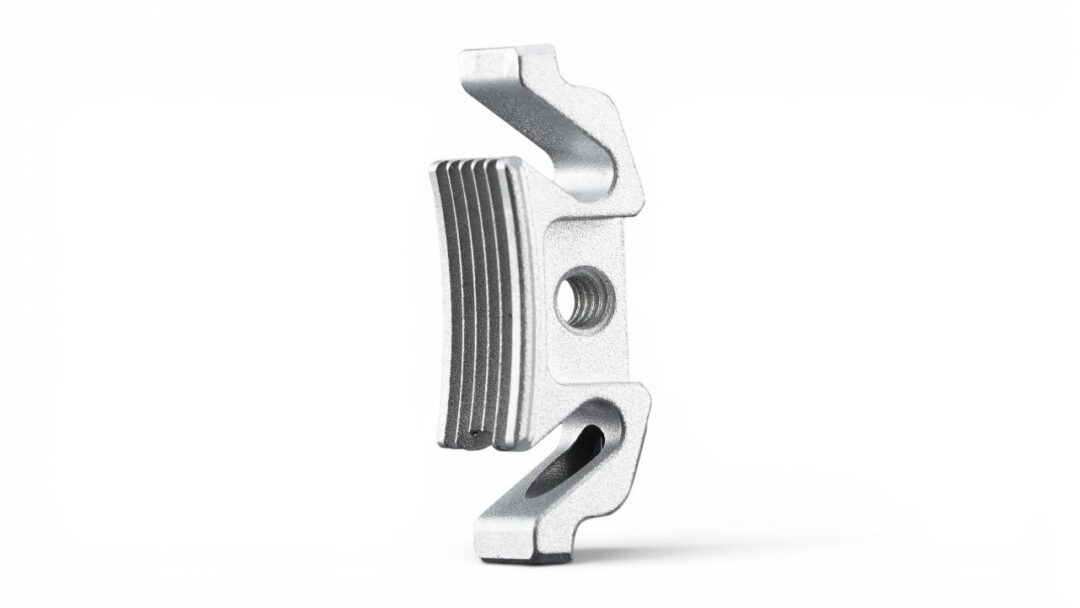 Metal mounting clamp with a grooved grip and central threaded hole for securing a part, silver finish, industrial hardware piece.