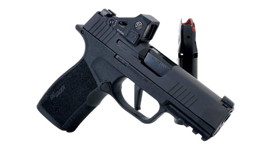 Side view of a black Sig Sauer semi-automatic pistol with a compact slide, textured grip, and a detachable magazine nearby.