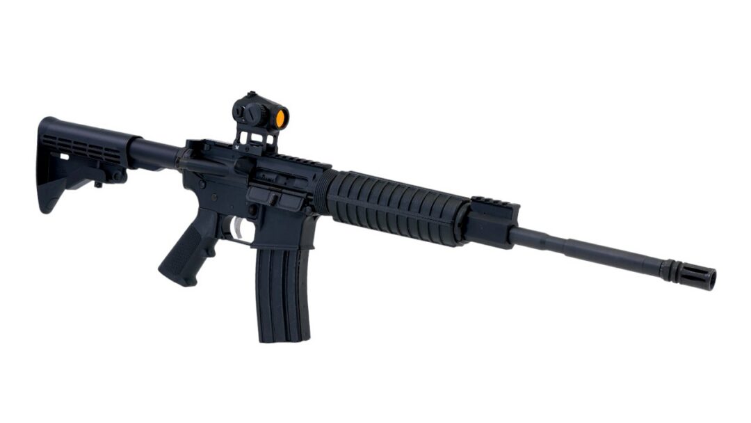 Black AR-style rifle with adjustable stock, scope sight, and long barrel shown in profile on a white background, isolated image