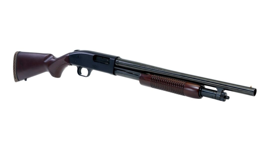Side view of a pump-action shotgun with a wooden stock and ribbed fore-end, laid horizontally on a white background.